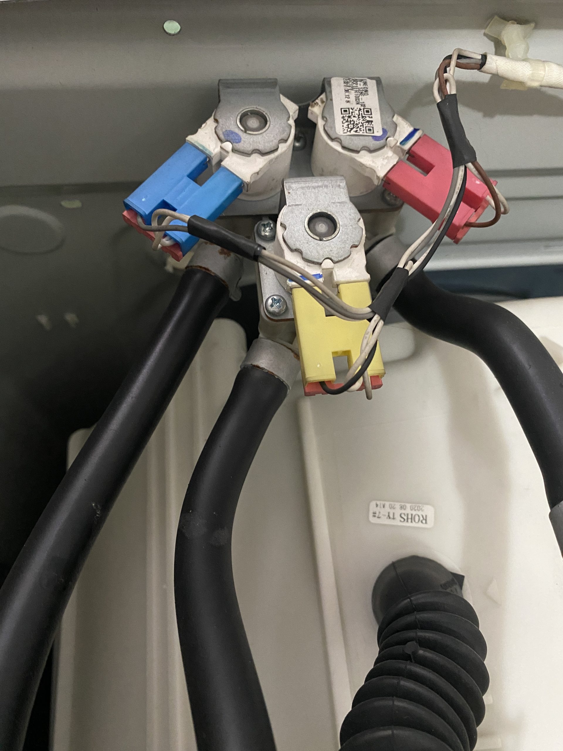 Triple water inlet valve assembly inside a washing machine during replacement