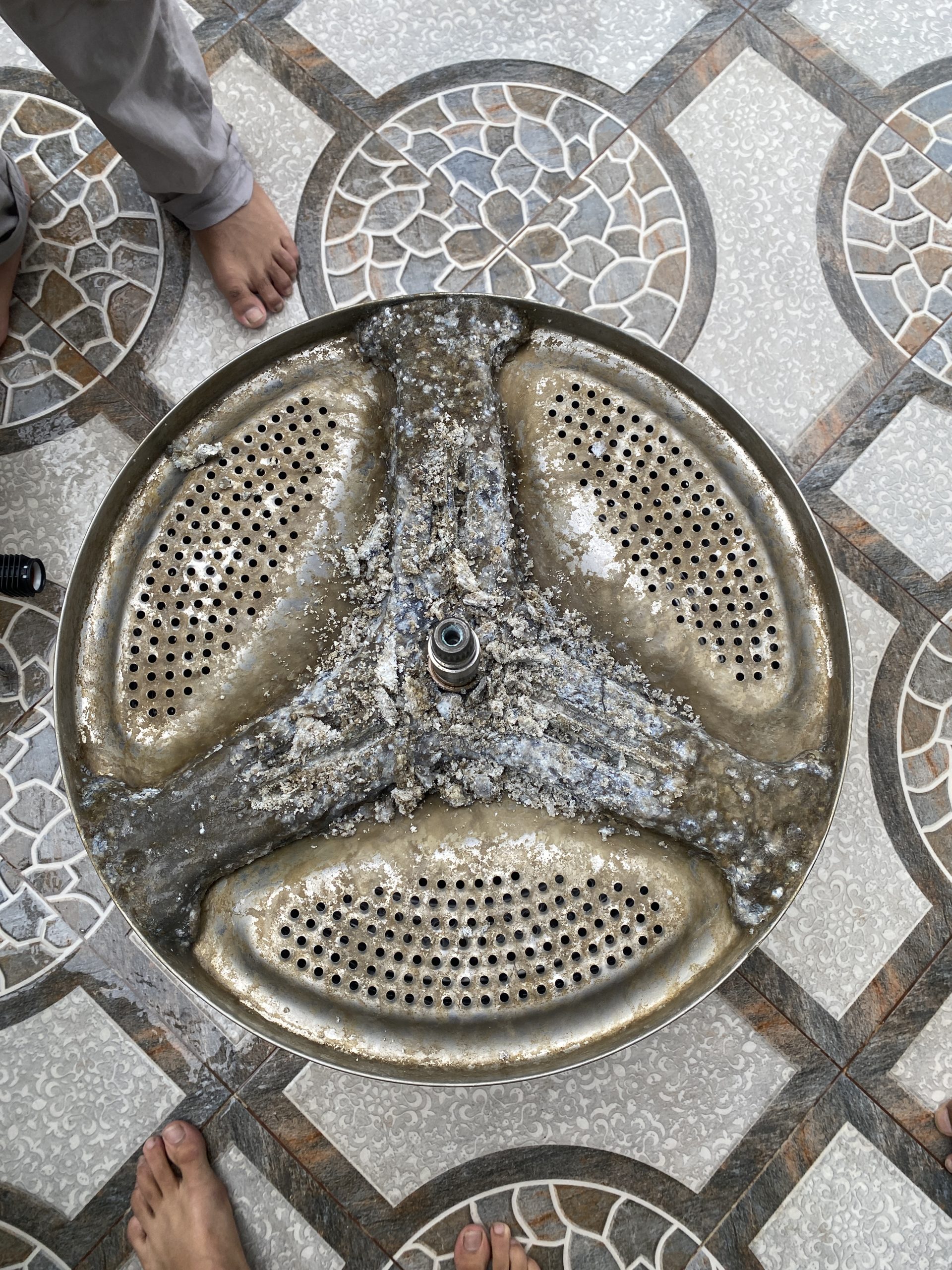 Pulsator plate removed from a top load washing machine, caked with scale and sludge
